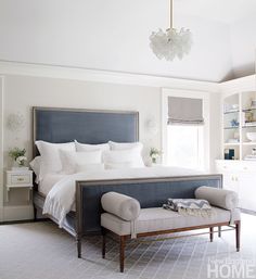 a bedroom with a bed, two chairs and a chandelier hanging from the ceiling