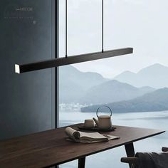 a wooden table topped with a cup of coffee next to a wall mounted light fixture