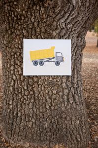 a postcard with a yellow truck on it is attached to a tree in the park