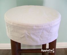 a white round ottoman sitting on top of a wooden stool