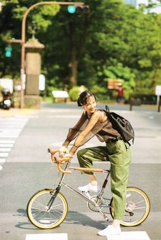 a man riding a bike down a street next to a cross walk with trees in the background