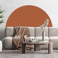 a living room with a couch, coffee table and potted plant in front of an orange circle