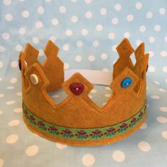 a felt crown with buttons on it sitting on a polka dot tablecloth covered surface