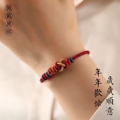 a woman's hand with a red and blue bracelet on her wrist, in chinese characters