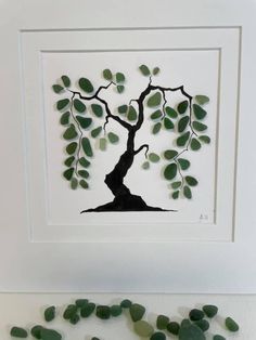 a tree made out of sea glass sitting on top of a white table next to some rocks