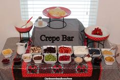 a table topped with lots of food next to a sign that says crepe bar