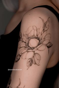 a woman's arm with flowers and leaves tattooed on the back of her shoulder