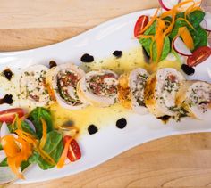 a white plate topped with meat and veggies on top of a wooden table