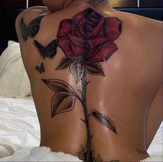 the back of a woman's body with tattoos on it and a rose tattoo