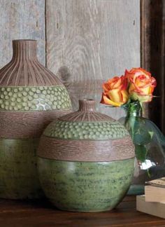 three green vases sitting on top of a wooden table next to a flower pot