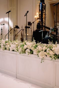 white flowers and greenery line the side of a stage