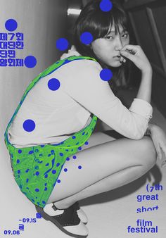 a woman sitting on top of a white floor next to a blue and green polka dot poster