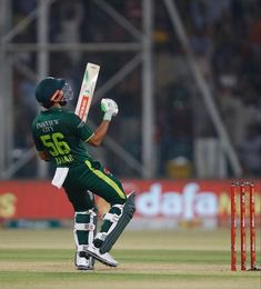 a man in green and yellow uniform playing a game of cricket