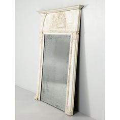 an old white mirror sitting on top of a table next to a wall mounted shelf