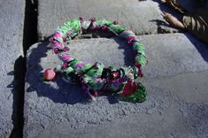 a bracelet is sitting on the ground next to some rocks and leaves with beads hanging from it