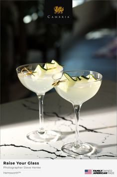 two glasses filled with white liquid and garnished with green leaves on the rim