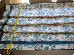 a blue and white flowered curtain with a measuring tape