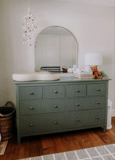 a dresser with a mirror and teddy bear sitting on top of it in a room