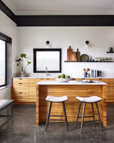 two stools in front of a kitchen island with an open shelf on the wall