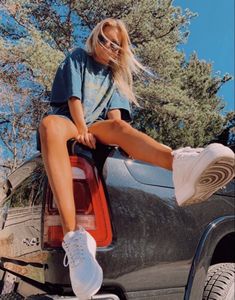 a woman sitting on the back of a car with her legs up in the air