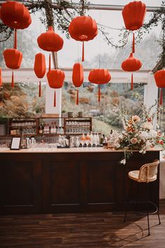 a bar with red lanterns hanging from it's ceiling and flowers on the counter