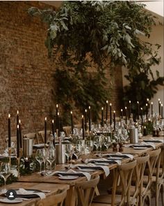 the table is set with candles and place settings for an elegant dinner or reception in front of a brick wall