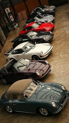 a row of cars parked next to each other on top of a cement floor in front of a building