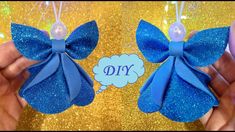 two blue bows with the word diy hanging from them on a gold glitter background