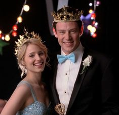 a man in a tuxedo standing next to a woman wearing a tiara