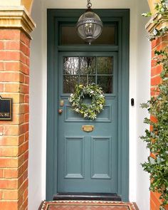 a blue front door with a wreath hanging on it's side and a light fixture above the door