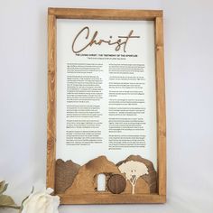 a wooden framed sign with the words christ and sheeps on it, next to a white flower