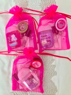 three pink bags filled with personal care items on top of a white tableclothed surface