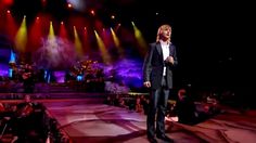 a man standing on top of a stage in front of colorful lights and microphones