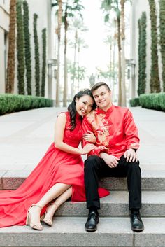 a man and woman are sitting on the steps together in front of some palm trees