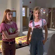 two young women standing next to each other in front of a table with donuts on it