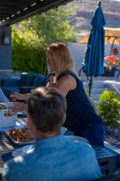 people sitting at an outdoor table eating food