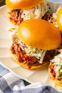 three pulled pork sliders on a white plate with coleslaw and slaw