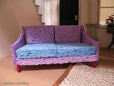 a purple and blue couch sitting on top of a rug next to a stair case