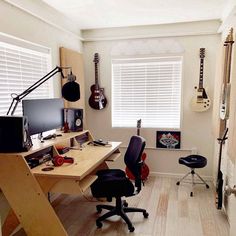 a room with guitars, guitar stands and desks in the corner on the wall