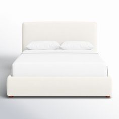 a bed with white linens and pillows on it's headboard is shown