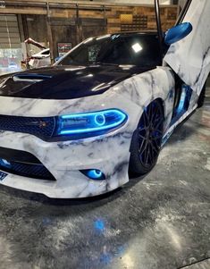 a white and black car with blue lights on it's front bumper is parked in a garage