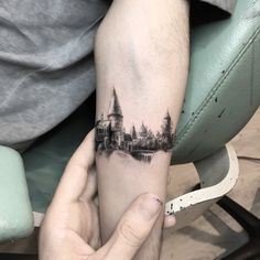 a person with a tattoo on their arm holding up a small piece of art that looks like a castle