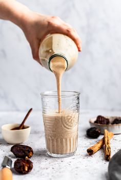 someone pouring coffee into a glass with cinnamons and raisins on the side