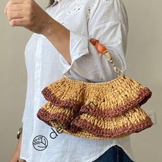 a woman is holding a straw purse and pointing at the camera with her thumb up