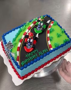 a birthday cake that is shaped like a race track with two people on the track