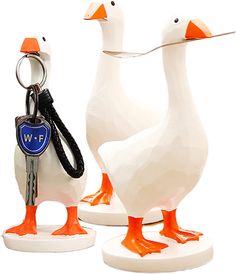 two white ducks with orange beaks holding keys