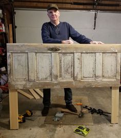 a man standing behind an old dresser in a garage