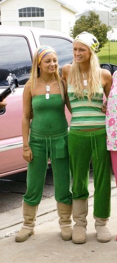 three young women standing next to each other in front of a pink car and truck