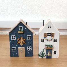 two small wooden houses sitting on top of a wooden floor next to each other with snowflakes hanging from them