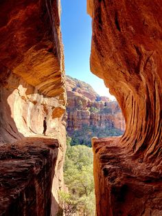 an open window in the side of a cliff with trees and mountains in the background